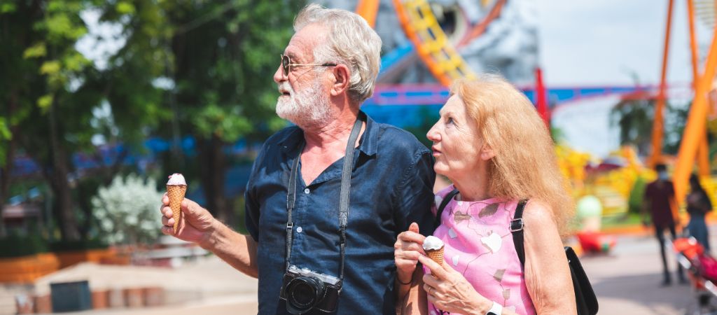 Senior Couple Looks Intrigued at an Amusement Park Older couple eating ice cream and looking around at an amusement park.